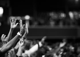 pexels-photo-2014773-2014773 Black and white image of audience with hands raised, capturing concert energy.